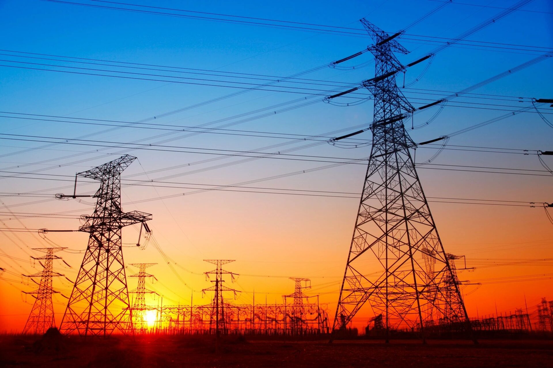 A sunset with power lines and towers in the background.